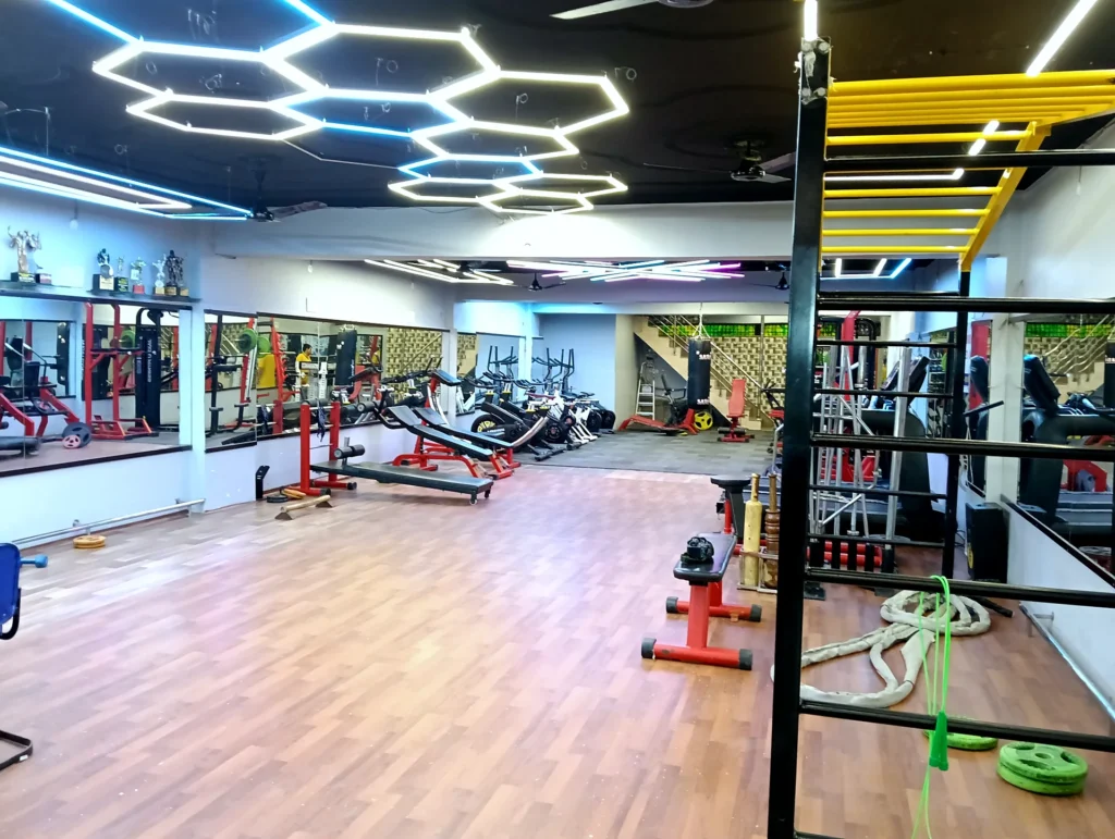 Modern spacious gym interior with mirrors and exercise equipment at Arya Fitness